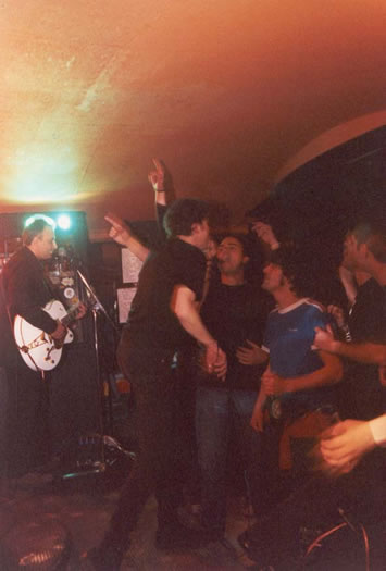 The Cynics performing live, with fans reaching toward the stage